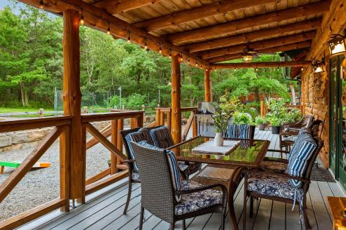 a wooden deck with a table and chairs at The Bigwood Cabin by AvantStay Hot Tub Firepit Pool Table Private Yard in Long Pond