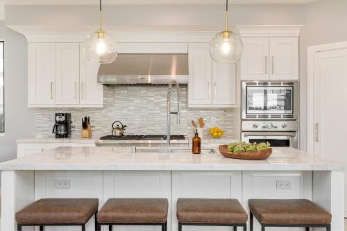 a kitchen with white cabinets and a counter with stools at Sea Crown by AvantStay 5mins from the Beach w Multiple Terraces PermitSLP13639 in Newport Beach
