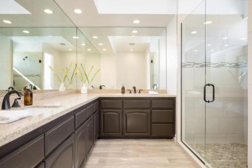 a bathroom with two sinks and a shower at Buena Vista by AvantStay Massive Outdoor Oasis w Pool Spa Firepit in La Quinta