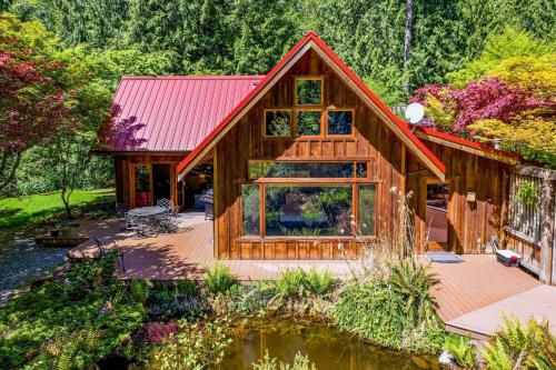 a log cabin with a red roof and a pond at Rhythm Waters by AvantStay Garden Paradise Pond in Langley