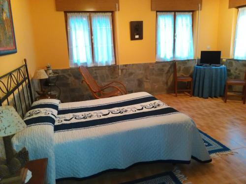 a bedroom with a bed and a table and windows at Apartamentos Rurales Casa El Caminero in Merás