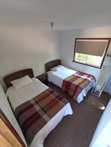 a hotel room with two beds and a window at Cabañas y Agroturismo El Trolofken in Pocuno