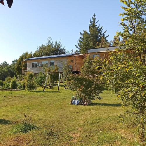 a house in a field with a swing at Cabañas El Trolofken in Pocuno