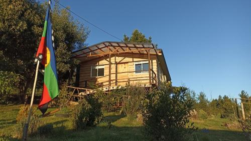 a tree house with a flag in front of it at Cabañas El Trolofken in Pocuno