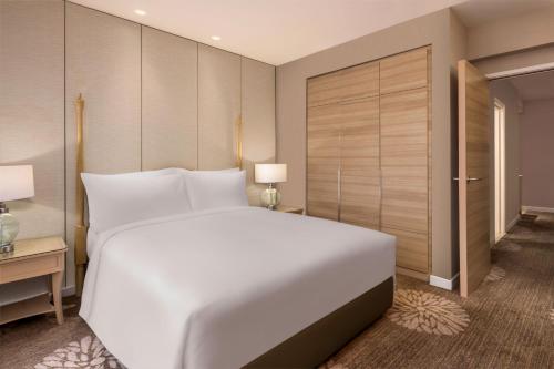 a bedroom with a large white bed and a closet at Dusit Princess Melaka in Melaka