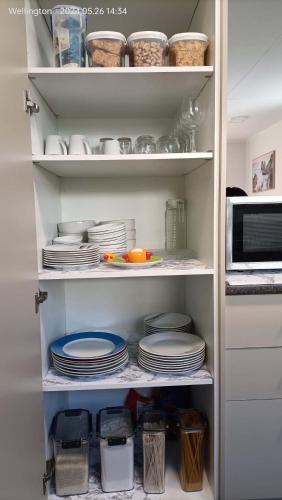 a kitchen pantry with plates and dishes on shelves at Comfy & Sunny home in Wellington--3 Heat Pumps in Wellington