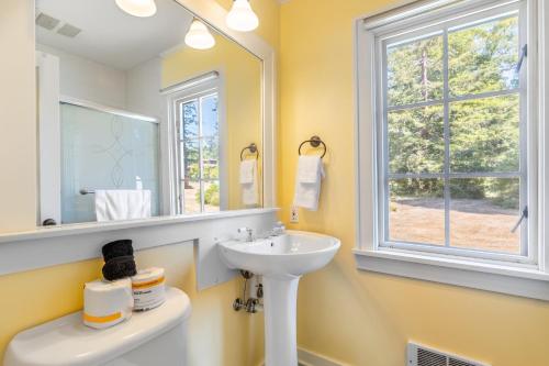 a bathroom with a sink and a mirror and a window at Smugglers Lagoon Beach Cottage by AvantStay in Greenbank