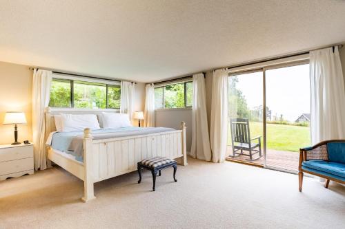 a bedroom with a bed and a chair and windows at Private Beach Access Water Views Sleeps 18 Historic 6BDR Farmhouse w Deck in Clinton