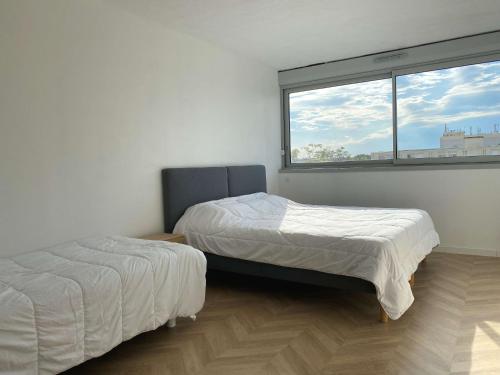 deux lits dans une chambre avec une fenêtre dans l'établissement Spacieux T2, dernier étage, confort moderne, Wi-Fi, Balaruc-les-Bains - FR-1-553-276, à Balaruc-les-Bains