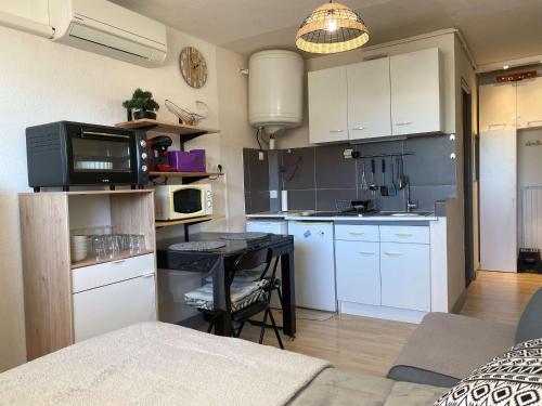 une cuisine avec des armoires blanches et une table dans une pièce dans l'établissement Studio confort avec climatisation et wifi à Balaruc-les-Bains - FR-1-553-278, à Balaruc-les-Bains