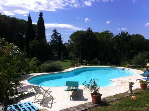 una piscina en un patio con sillas y árboles en Villa Arianna B&B, en Lari