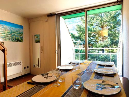 une table avec des verres, des assiettes et une fenêtre dans l'établissement Duplex T3 6 pers - Saint-Lary-Soulan avec TV, parking, casier à skis - FR-1-457-352, à Saint-Lary-Soulan