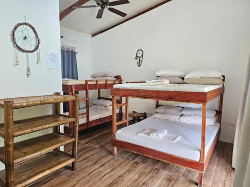 a room with three bunk beds and a ceiling fan at Big BamBoo Beach Resort Sipalay in Sipalay