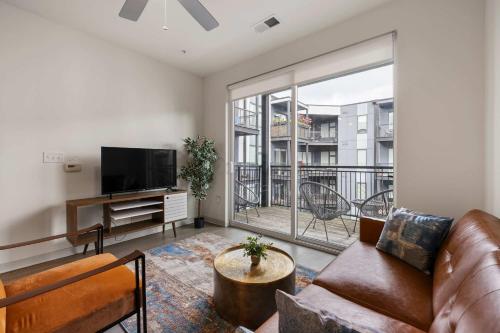 a living room with a couch and a large window at Modern Nulu 2BR CozySuites 09 in Louisville