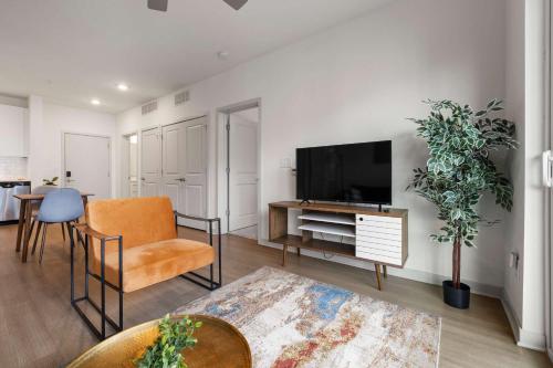 a living room with a tv and a chair and a table at Modern Nulu 2BR CozySuites 09 in Louisville