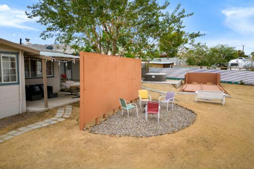 a group of chairs sitting in a yard next to a house at Fable by AvantStay 2 Unique Spaces w Bowling Hot Tub Fire Pit Large Yard in Joshua Tree