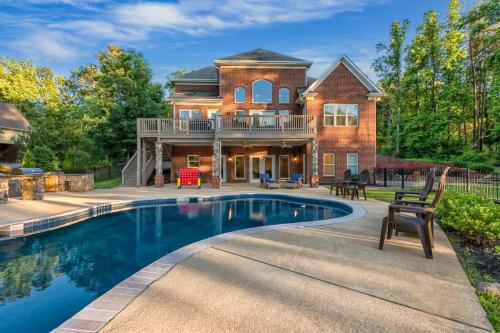 a home with a swimming pool in front of a house at Lake Escape by AvantStay Lakefront Private Dock in Mooresville