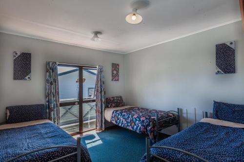 a room with two beds and a balcony with the ocean at Ivorytowers Accommodation in Fox Glacier