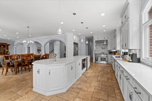 a kitchen with white cabinets and a dining room at Flip Flop Therapy by AvantStay Lakefront Home w Game Room Dock Access in Mooresville