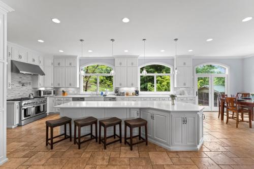a kitchen with white cabinets and a island with bar stools at Flip Flop Therapy by AvantStay Lakefront Home w Game Room Dock Access in Mooresville