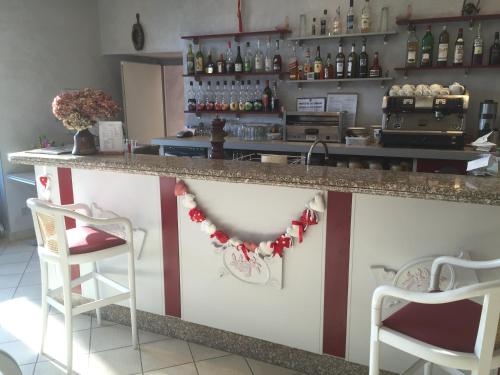 - un bar avec 2 chaises et un comptoir avec des bouteilles de vin dans l'établissement Hotel George, à Montmélian