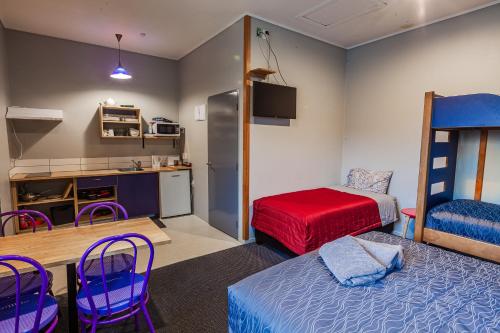 a room with a bed and a kitchen with a bunk bed at Ivorytowers Accommodation in Fox Glacier