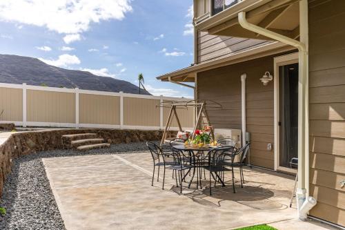 a patio with a table and chairs next to a house at Makaha Villa by AvantStay Mountain Ocean Views in Waianae