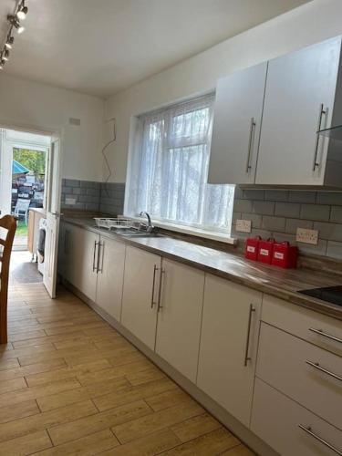 a kitchen with white cabinets and a large window at Spacious Grimsby Contractor Friendly Home Sleeps 12 and Free Parking in Grimsby