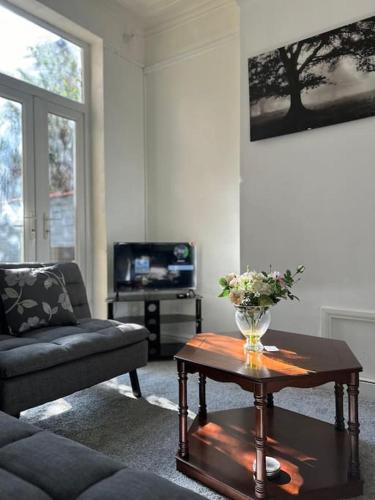 a living room with a vase of flowers on a table at Spacious Grimsby Contractor Friendly Home Sleeps 12 and Free Parking in Grimsby