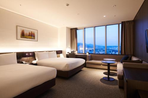 a hotel room with two beds and a couch at Nine Tree by Parnas Seoul Myeongdong 2 in Seoul