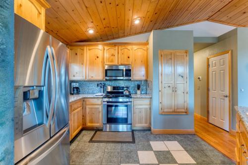 a kitchen with wooden cabinets and a stainless steel refrigerator at Golden Summit by AvantStay Stunning Secluded Cabin w Access to Tahoe Donner in Truckee