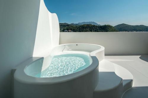 a bath tub with water in it on a balcony at Miyue Shenzhen Blue and White Holy Island Cliff Pool Hotel in Shenzhen