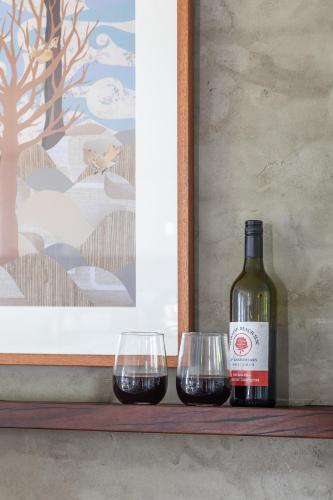 a bottle of wine and two wine glasses on a shelf at Sandy point hideaway in Sandy Point