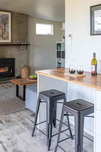 a kitchen with two bar stools and a fireplace at Sandy point hideaway in Sandy Point
