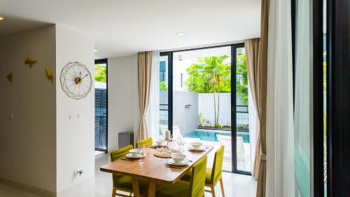 a dining room with a wooden table with yellow chairs at Laguna Park 2 Family Pool Villa near Bang Tao Beach in Bang Tao Beach