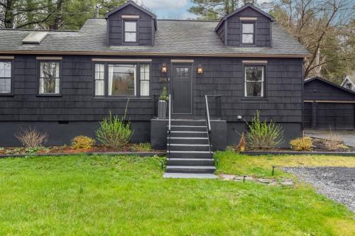 a black house with a green lawn in front of it at Charcoal Chalet by AvantStay A Design w Firepit in New Paltz