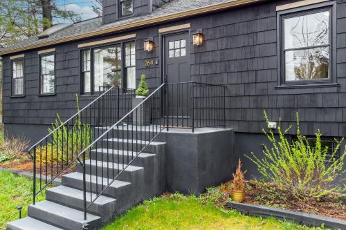 a black house with a staircase in front of it at Charcoal Chalet by AvantStay A Design w Firepit in New Paltz