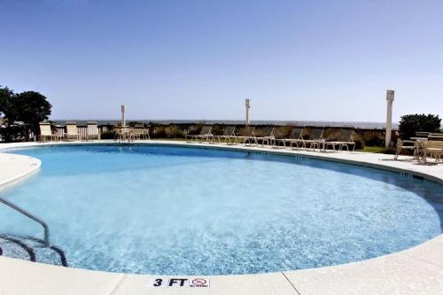 a large blue swimming pool with chairs and tables at 512 Seascape by AvantStay Oceanfront Condo on the Beach Community Pool Access in Isle of Palms