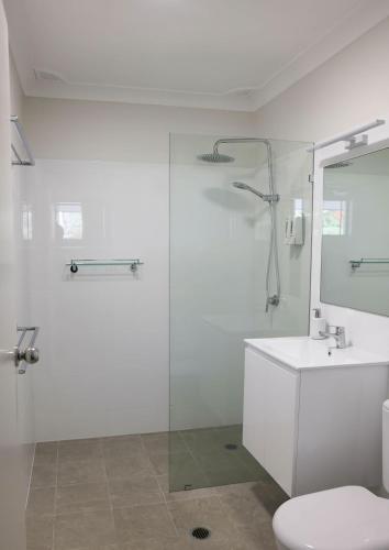 a bathroom with a shower and a toilet and a sink at Smugglers On The Beach in Coffs Harbour