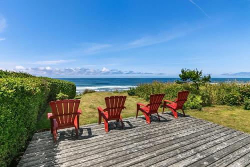 a group of four chairs sitting on a deck with the beach at The Pilot House by AvantStay Stunning Home Right On Arch Cape Beach in Arch Cape