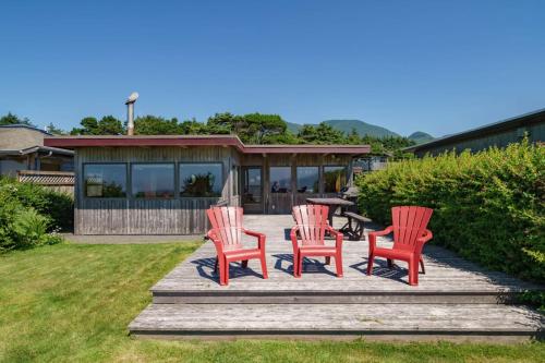 a group of four red chairs sitting on a deck at The Pilot House by AvantStay Stunning Home Right On Arch Cape Beach in Arch Cape