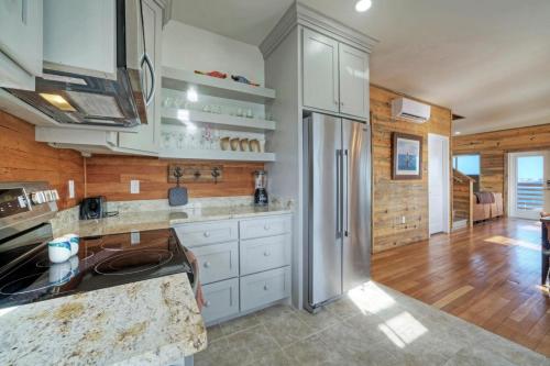 a kitchen with white cabinets and a stainless steel refrigerator at Waterfront w Bay Views Shared Pool Boat Dock Marlin Madness by AvantStay in Padre Island