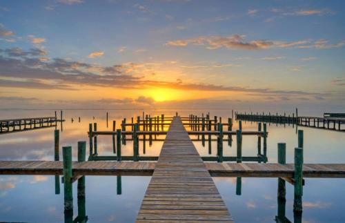 a dock in the water with a sunset at Waterfront w Bay Views Shared Pool Boat Dock Marlin Madness by AvantStay in Padre Island
