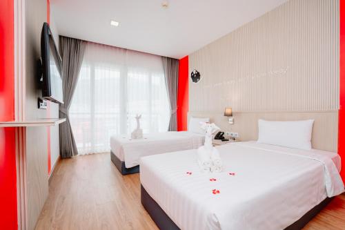 two beds in a hotel room with red walls at SLEEP WITH ME HOTEL design hotel @ patong (SHA Plus+) in Patong Beach