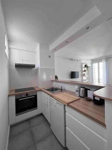 - une cuisine avec des murs blancs et un comptoir en bois dans l'établissement Le Point d'Eiffel - Au Cœur de Grenelle, à Paris