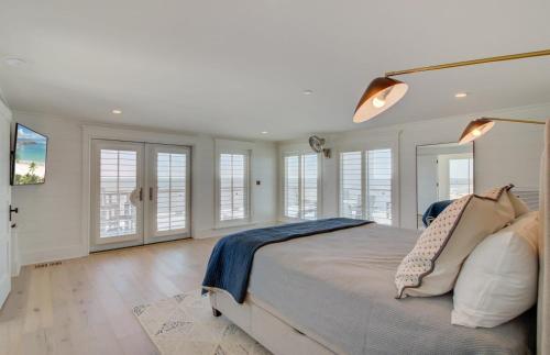 a bedroom with a large bed with white walls and windows at 710 Ocean Boulevard AvantStay Oceanfront Private Pool Rooftop Deck in Mount Pleasant