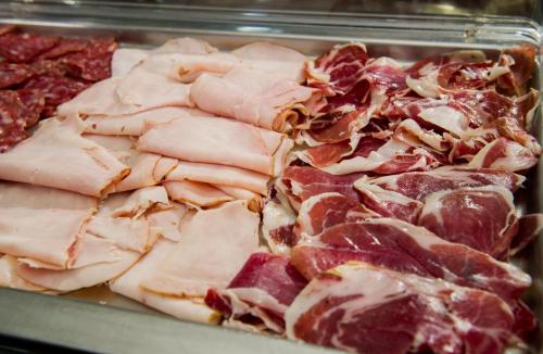 a bunch of ham and other meats in a tray at Hotel Actual in Barcelona