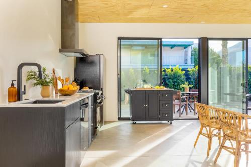 a kitchen with a sink and a counter with chairs at Blackhaus Full Buyout by AvantStay 16-Room Hotel in Palm Springs