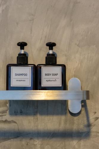 two bottles of shampoo and baby soap on a shelf at Nature Boutique Residence in Bangkok