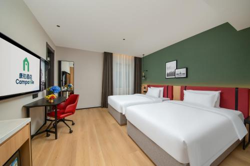 a hotel room with two beds and a tv at Campanile Nanjing South Station Daming Road in Nanjing